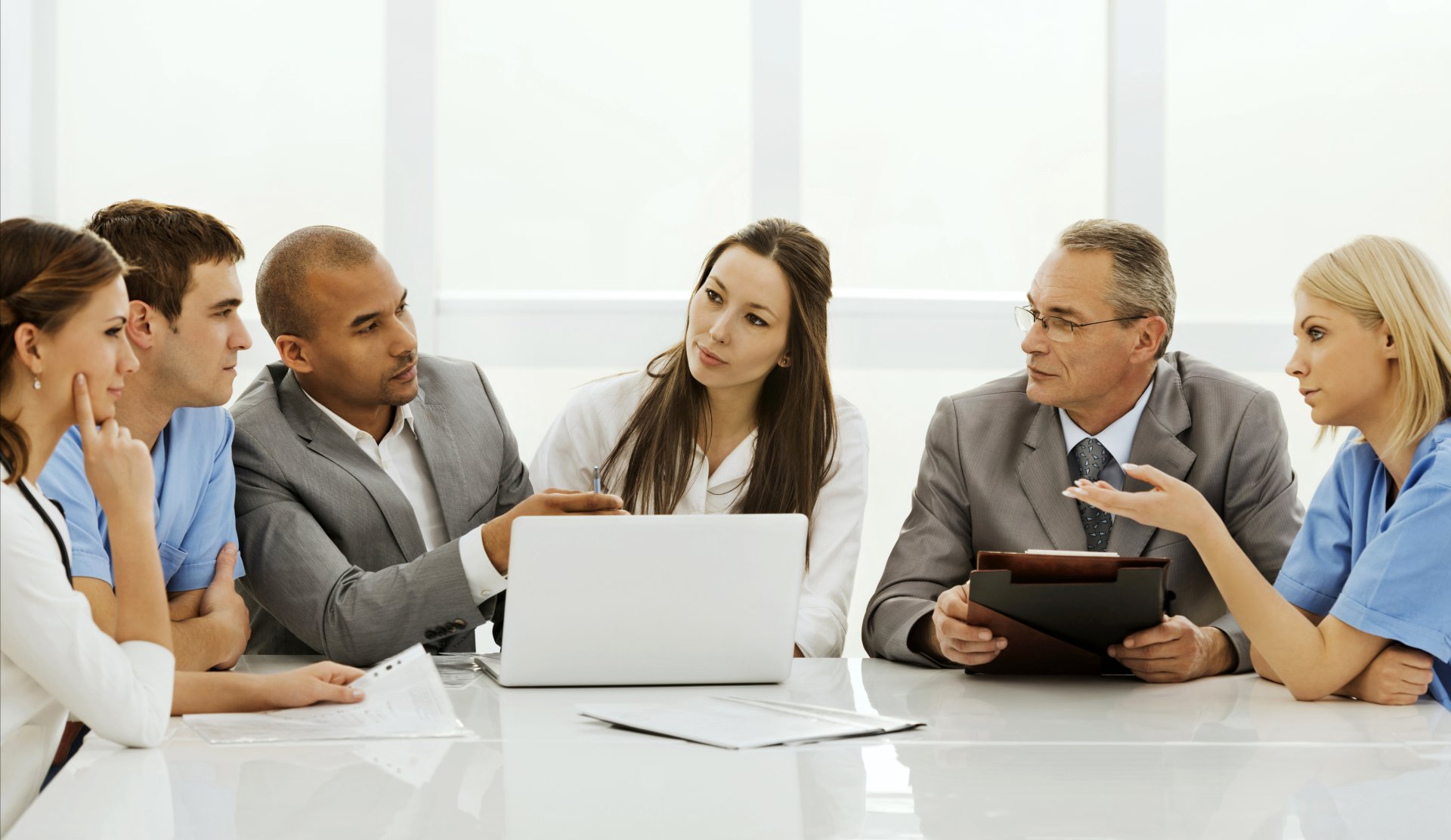 Six people in a meeting discussing over a laptop